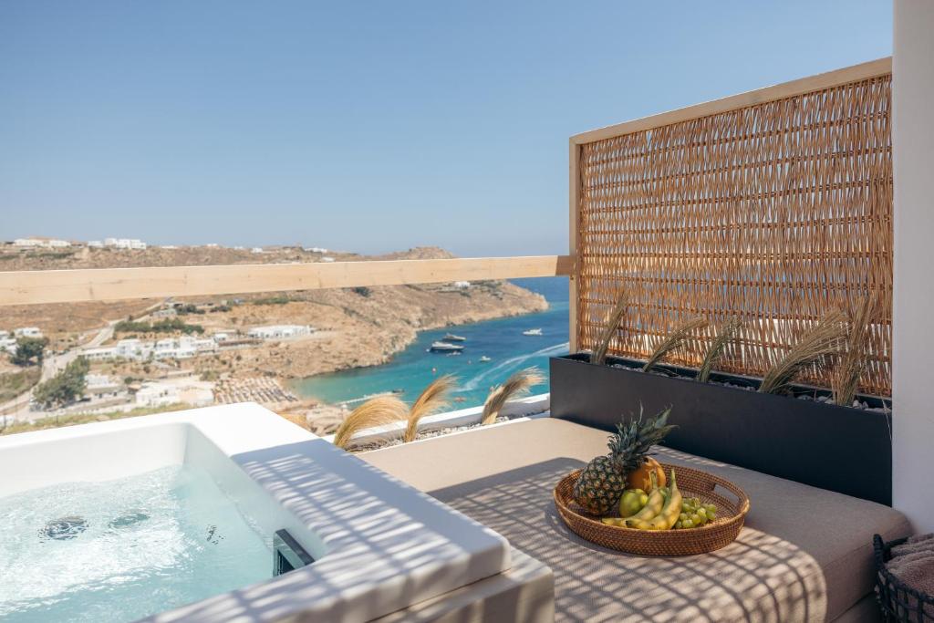 a bowl of fruit on a table on a balcony with a view of the ocean at Nimbus Lumen in Super Paradise Beach