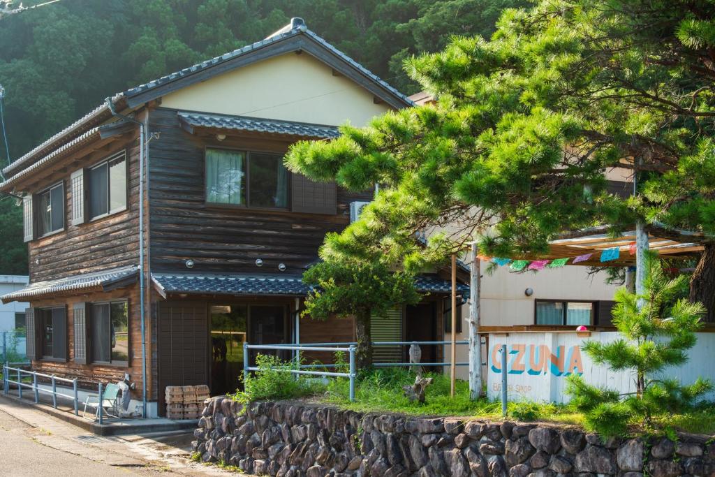 una casa de madera con un árbol delante en 大砂荘 OZUNA CAMP and LODGE en Kaiyo