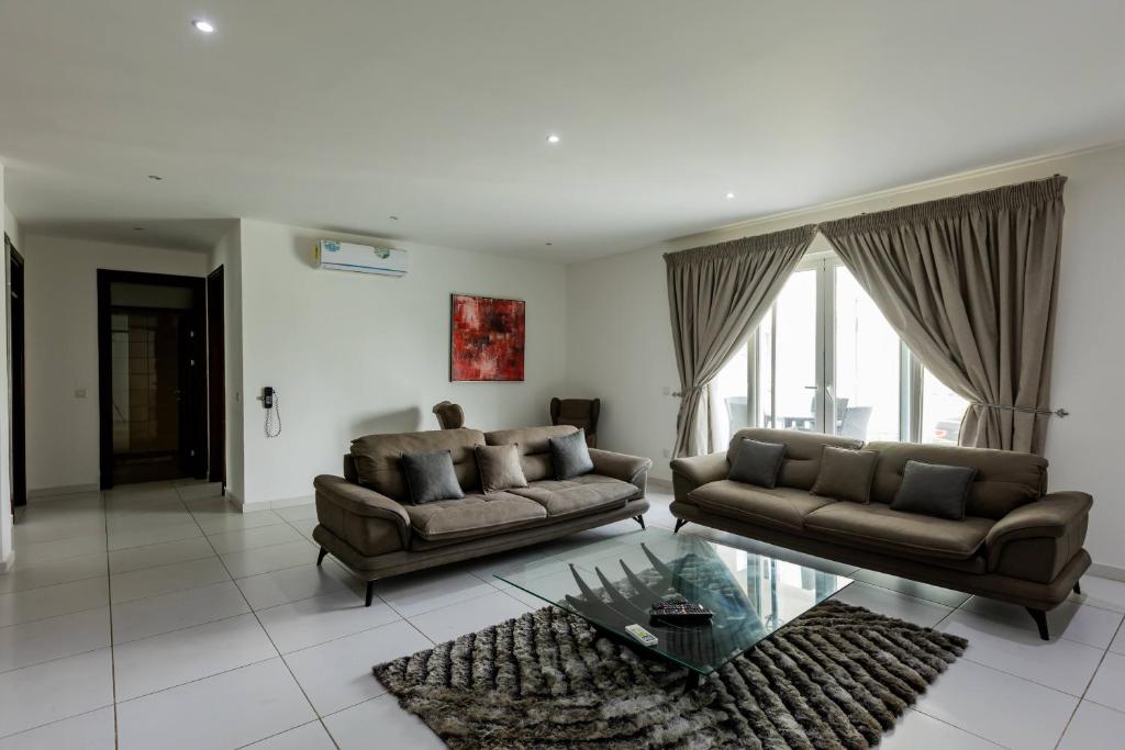 a living room with two couches and a glass table at Accra Fine Suites - Henrietta's Residences in Accra