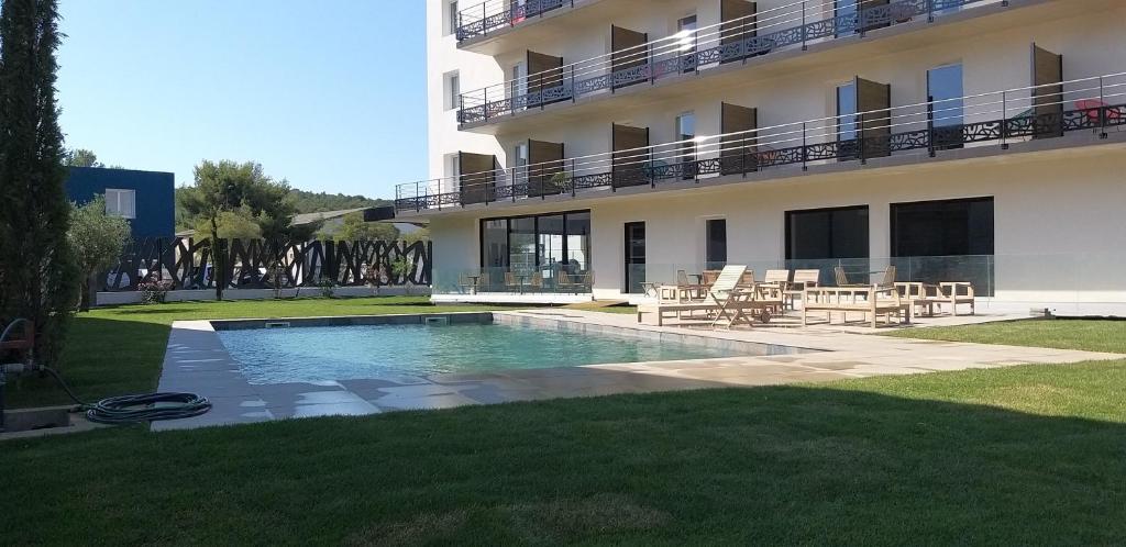 una piscina di fronte a un edificio di Golden Tulip Martigues Provence a Martigues