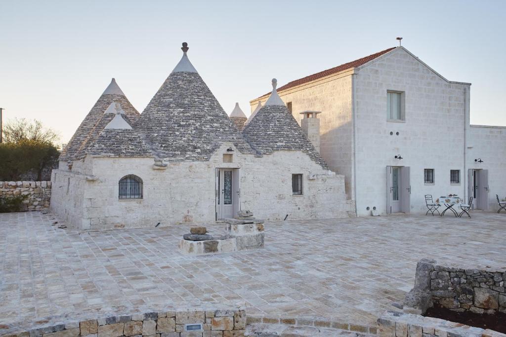 a large stone building with pointed roofs on a courtyard at Trulleria Tagliente in Alberobello