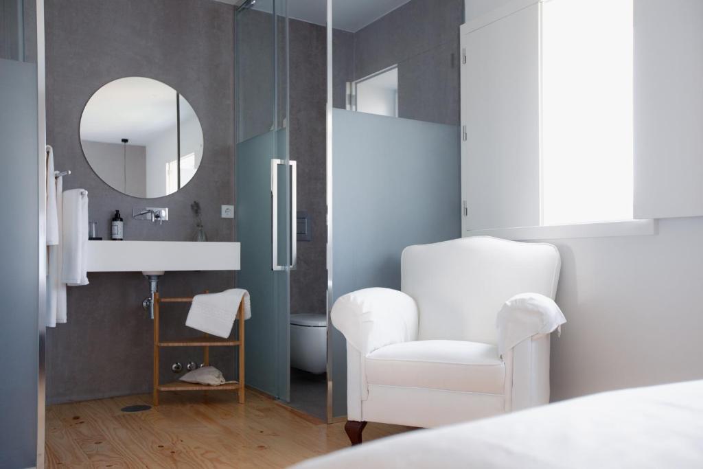 uma casa de banho com uma cadeira branca e um espelho. em Vila Real House em Vila Real