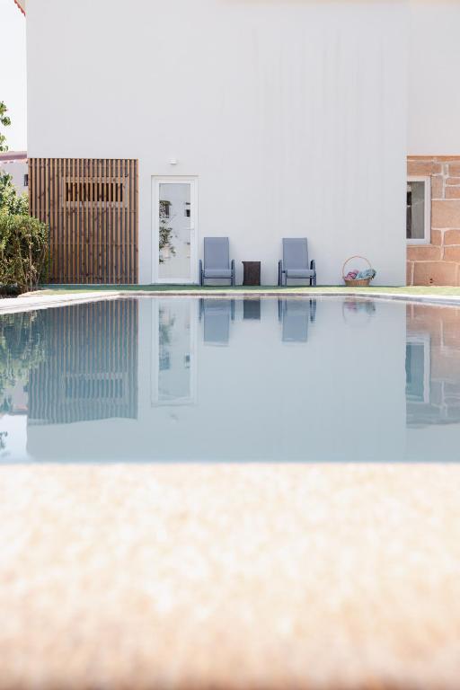 a swimming pool with two chairs and a house at Vila Real House in Vila Real