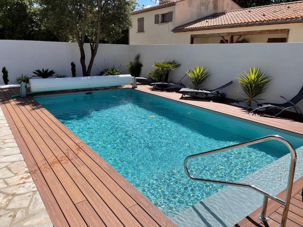 ein Pool mit einer Bank neben einem Haus in der Unterkunft Villa Brétignolles in Brétignolles-sur-Mer