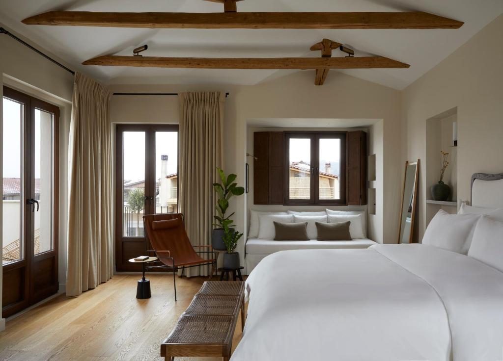 a bedroom with a large white bed and windows at The Storyteller Boutique House in Kalabaka