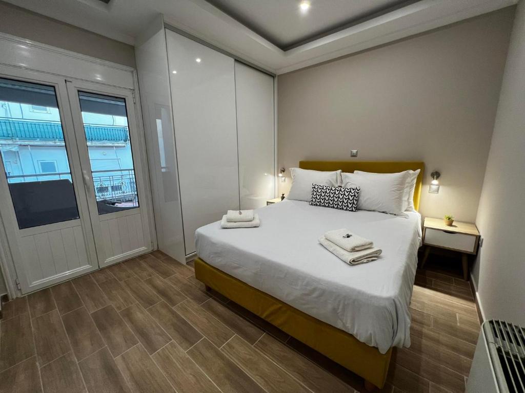a bedroom with a large white bed and a window at ATLANTIS APARTMENTS in Artemida