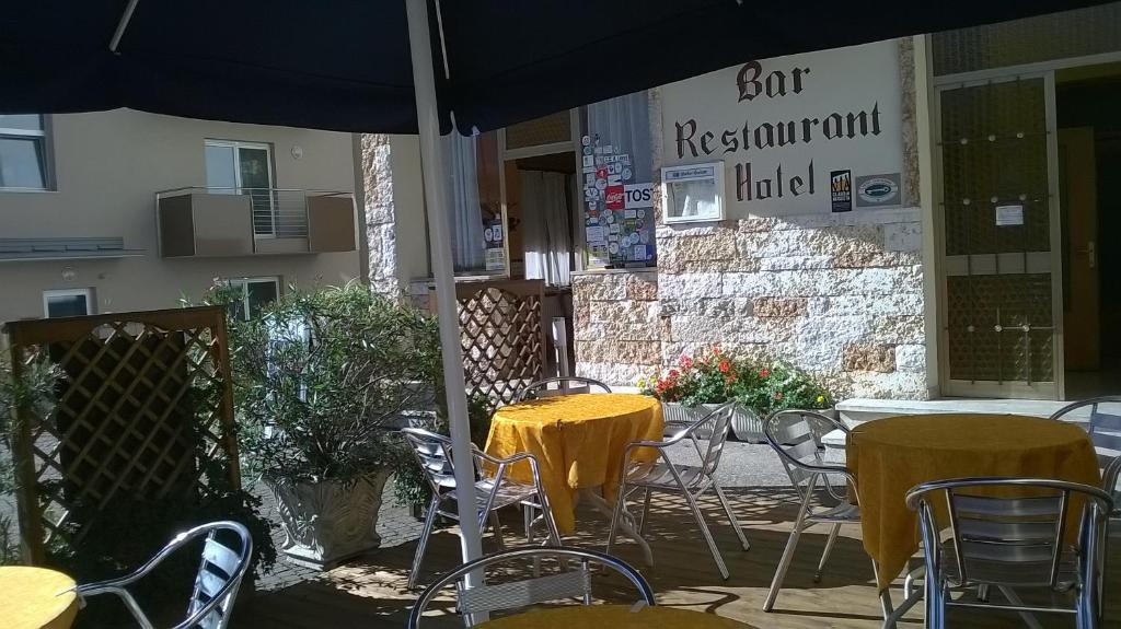 een patio met tafels en stoelen en een parasol bij Hotel Cantaleone in San Michele allʼAdige