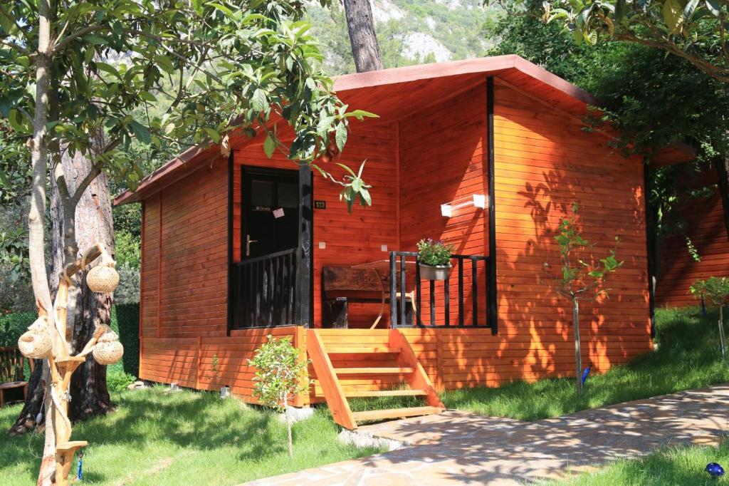 Cabaña de madera pequeña con porche y puerta en Olympos Robina Bungalov, en Olympos