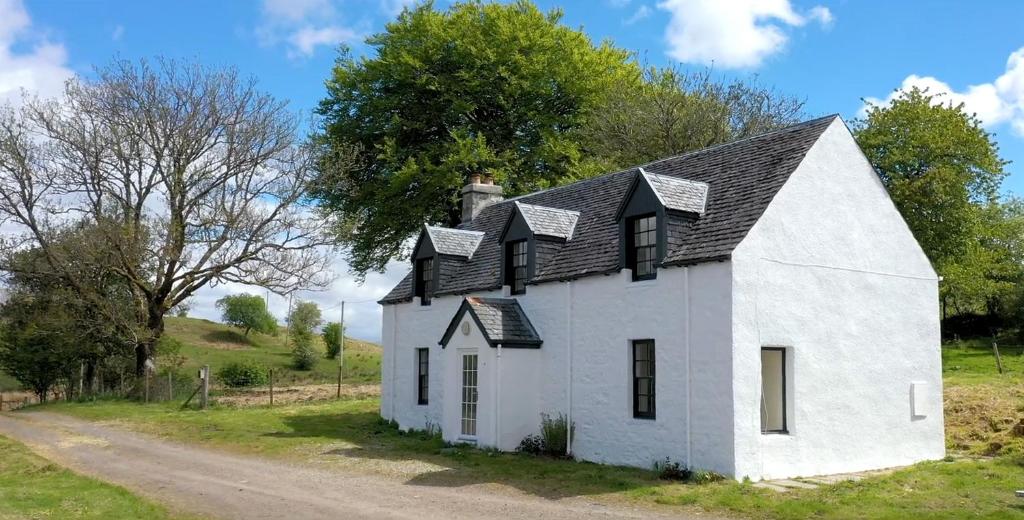 a white house with a black roof on a road at Achanlochan Farm in Taynuilt