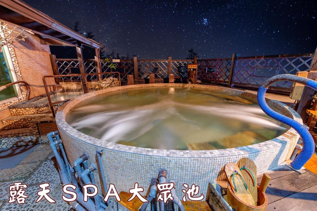 uma banheira de hidromassagem japonesa numa varanda à noite em Shankou Hotspring Hotel em Jiaoxi