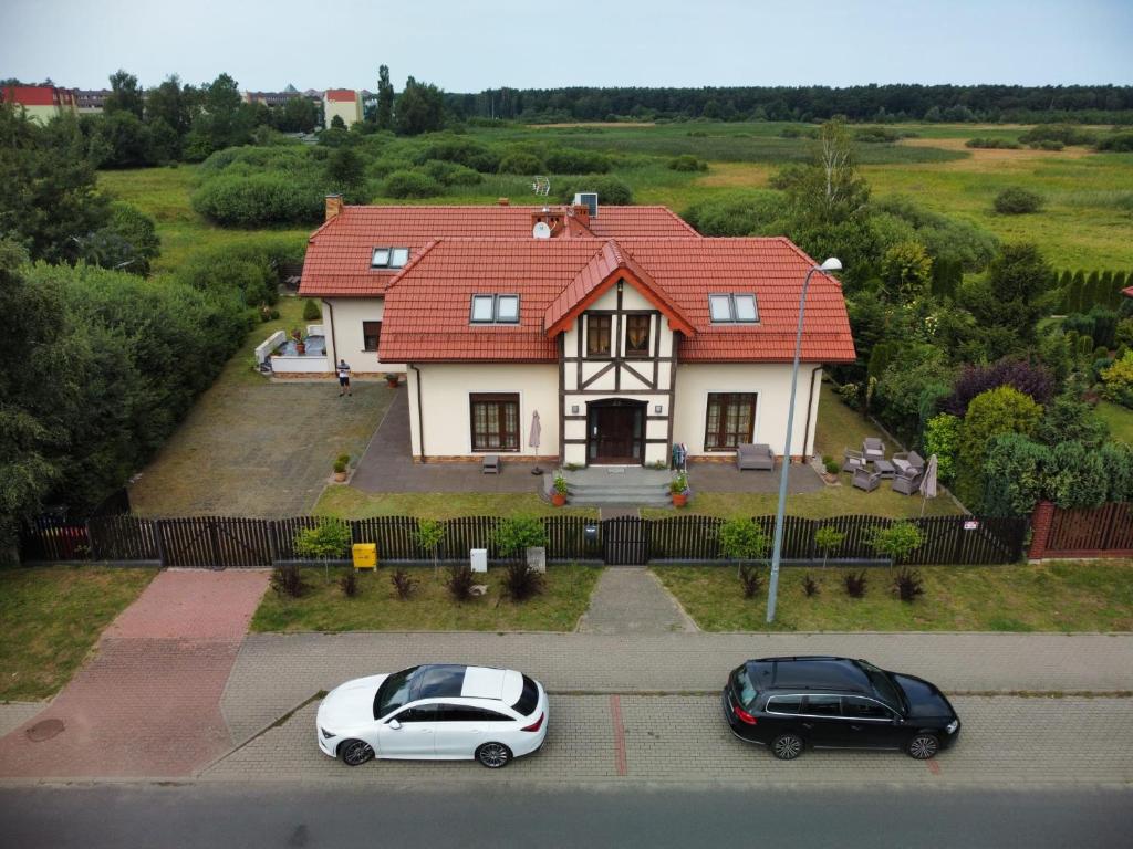 two cars parked in a parking lot in front of a house at Apartamenty z Klimatem in Ustka