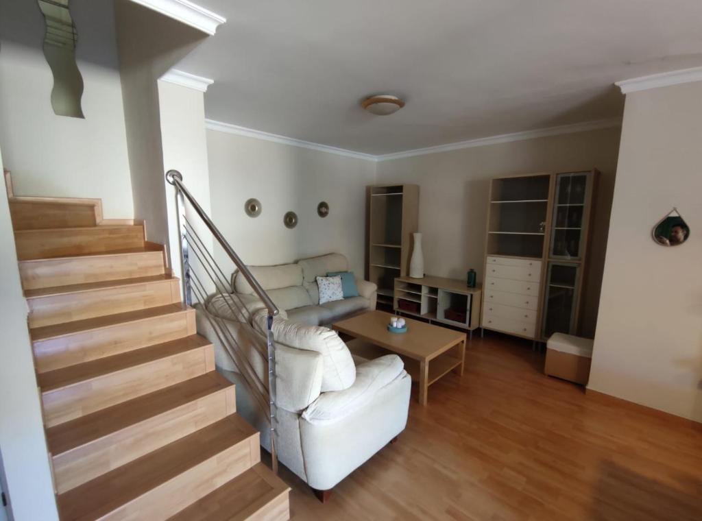 a living room with stairs and a white couch at Dúplex La Vega in Cenes de la Vega