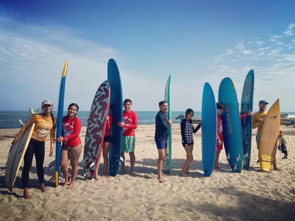 a group of people standing on the beach holding surfboards at HOSTAL Estrellas del tayrona playa in Santa Marta