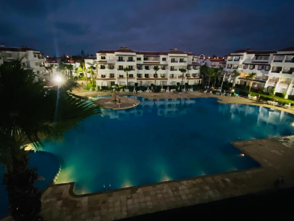 a large swimming pool in front of buildings at night at Superbe appartement en résidence avec piscine in Casablanca