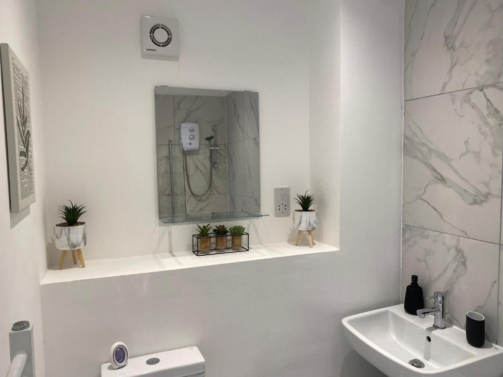 a white bathroom with a sink and a mirror at Hawton Crescent Wollaton Large Home with 4 Bedrooms Sleeps 8 People in Nottingham