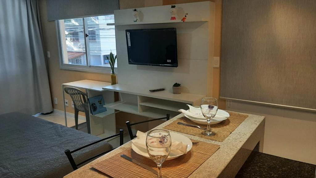 Habitación con mesa con 2 vasos y TV. en Apartamento Mania, en Vitória