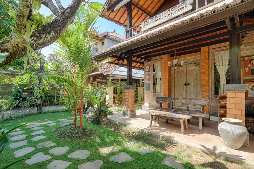 a patio of a house with a bench and a tree at Katang - Katang Guest House in Denpasar