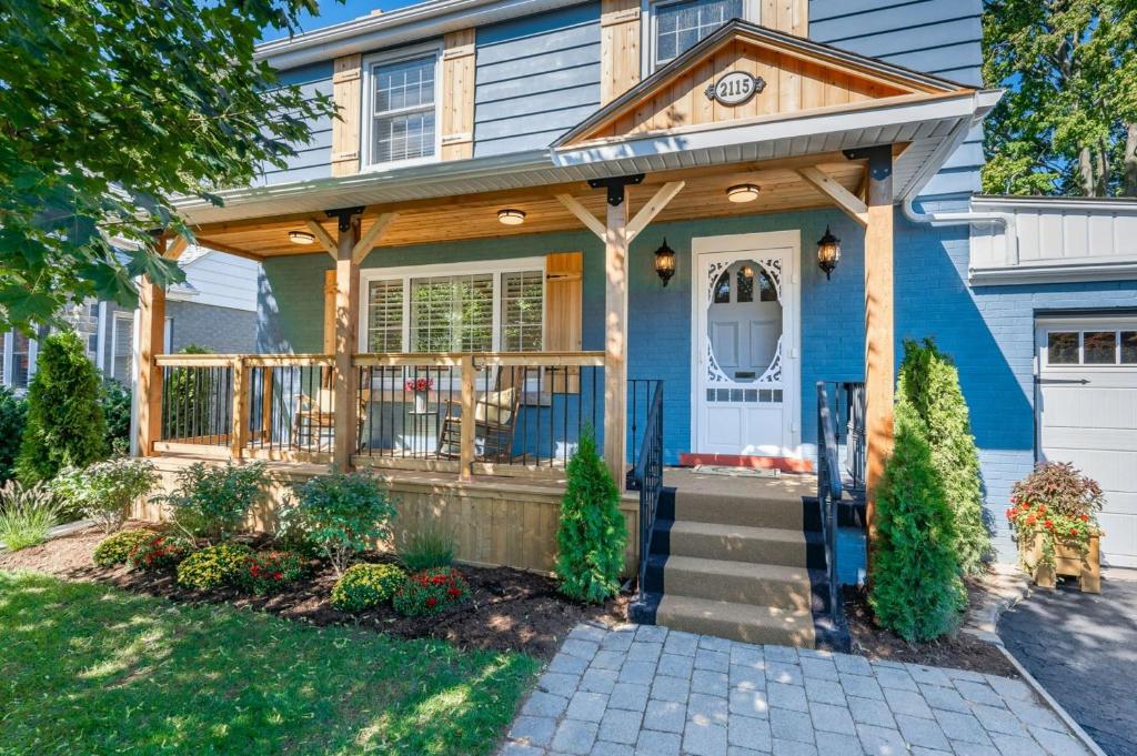 a blue house with a porch with a clock on it at 1 Bedroom Lower Level Suite in Burlington -The Jacob at Bellwood in Burlington