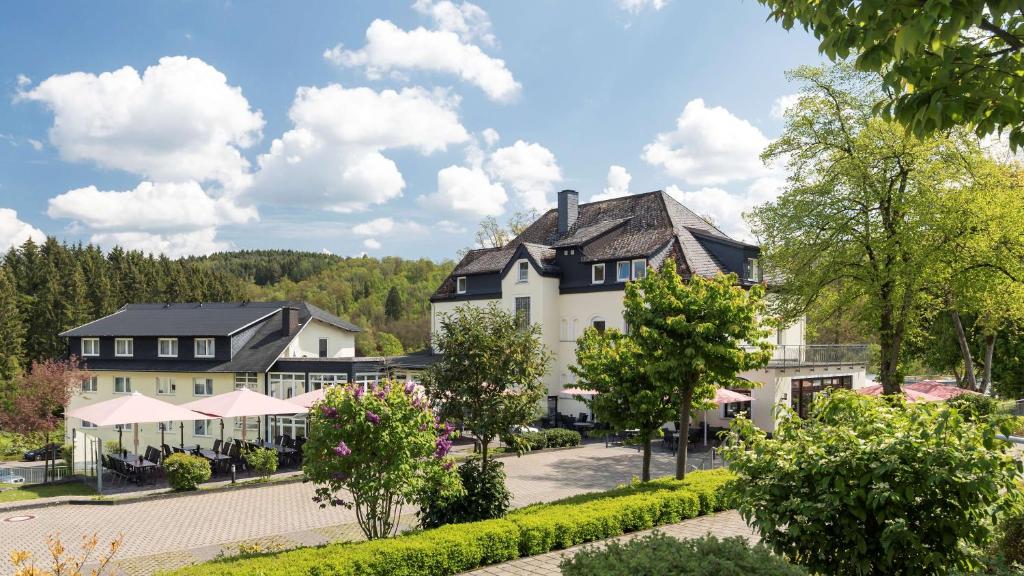 duży biały budynek z czarnym dachem w obiekcie Dorint Parkhotel Siegen w mieście Siegen