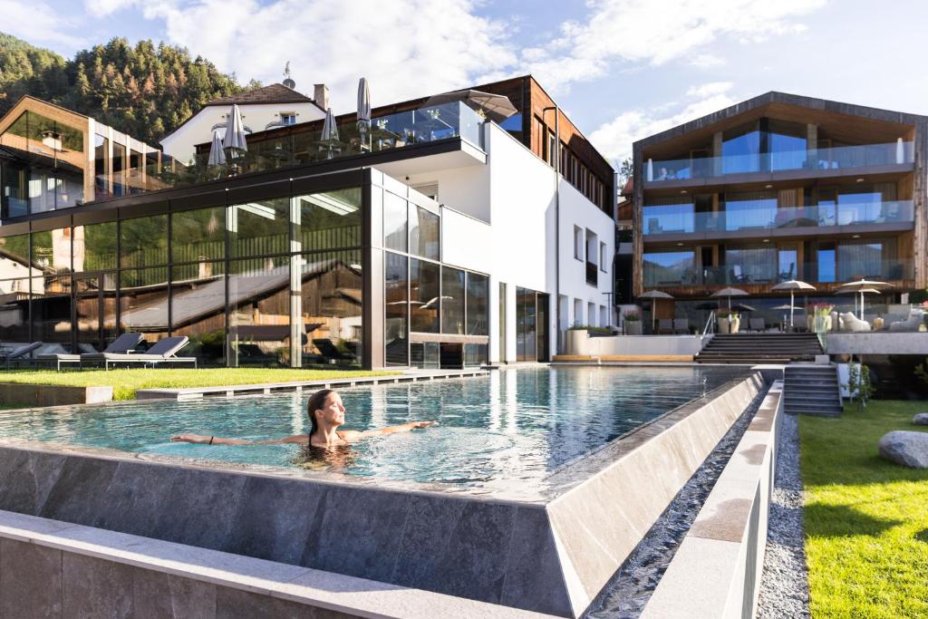 a woman in a pool in front of a building at Hotel Weisses Kreuz in Malles Venosta