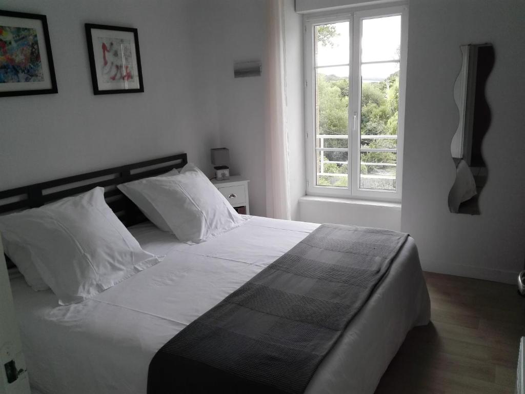 een slaapkamer met een groot wit bed en een raam bij L'APPART DU RIS in Douarnenez