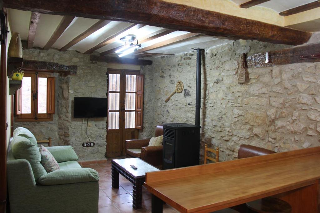 - un salon avec une télévision et un mur en pierre dans l'établissement Casa Rústica en Villafranca del Cid con vistas a la montaña "Els Arenals", à Villafranca del Cid