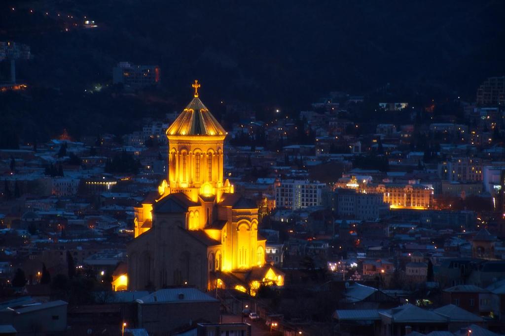 a building with a tower lit up at night at Roofs Tbilisi wine & rooms in Tbilisi City