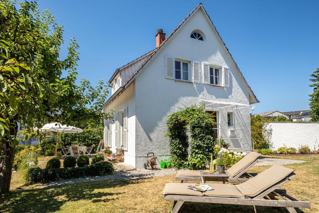 uma casa branca com espreguiçadeiras e um guarda-sol em Ferienhaus Immenstaad em Immenstaad am Bodensee