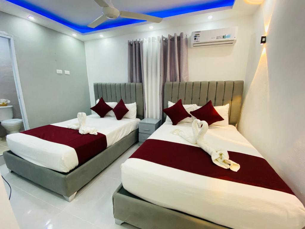 two beds in a hotel room with red and white pillows at Hotel Reloj in San Felipe de Puerto Plata