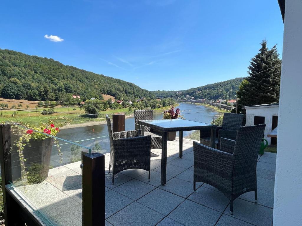 een patio met een tafel en stoelen en uitzicht op een rivier bij Saechsische-Schweiz-Ferienhaus-Wohnung-2-mit-hervorragendem-Panoramablick-ueber-das-Elbtal in Königstein an der Elbe