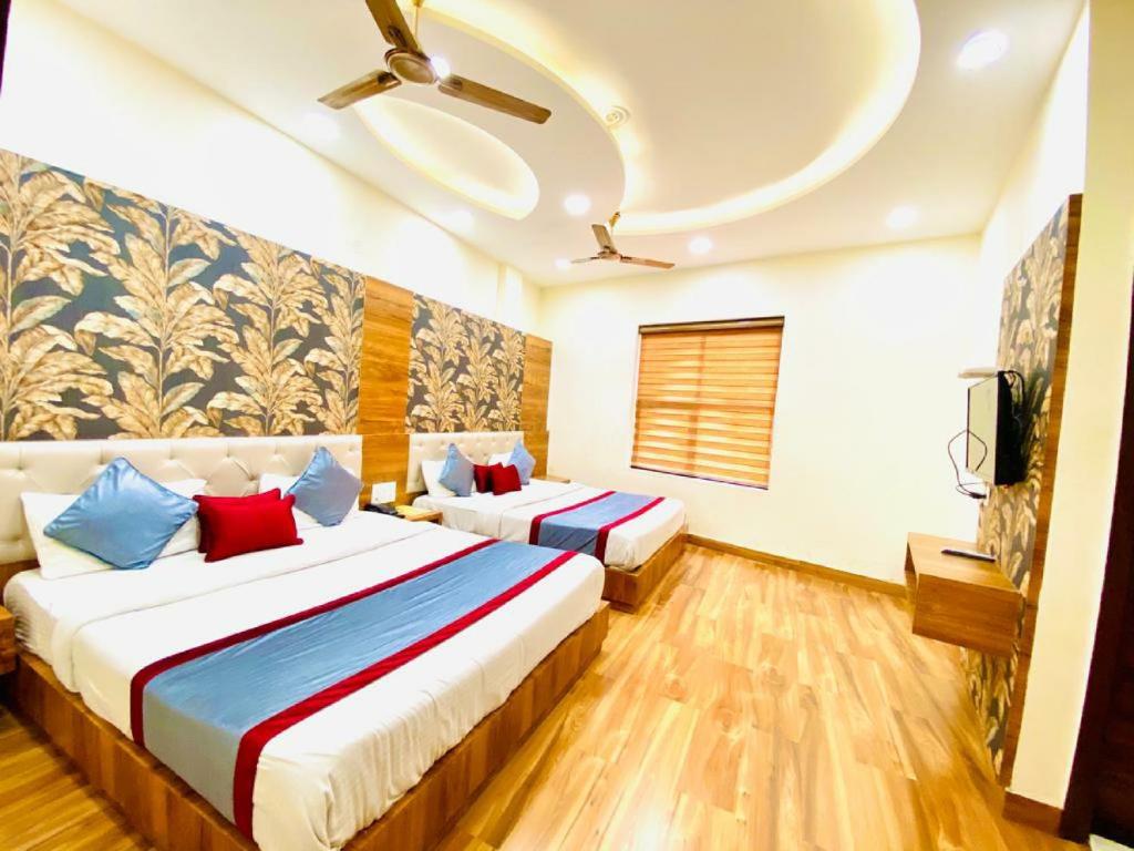 a hotel room with two beds and a tv at Avista Hotel in Amritsar