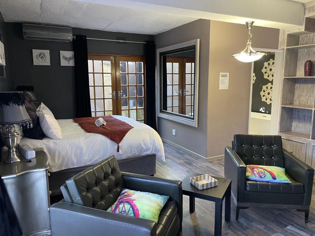 a bedroom with a bed and two chairs at @Grace Guesthouse in Klerksdorp