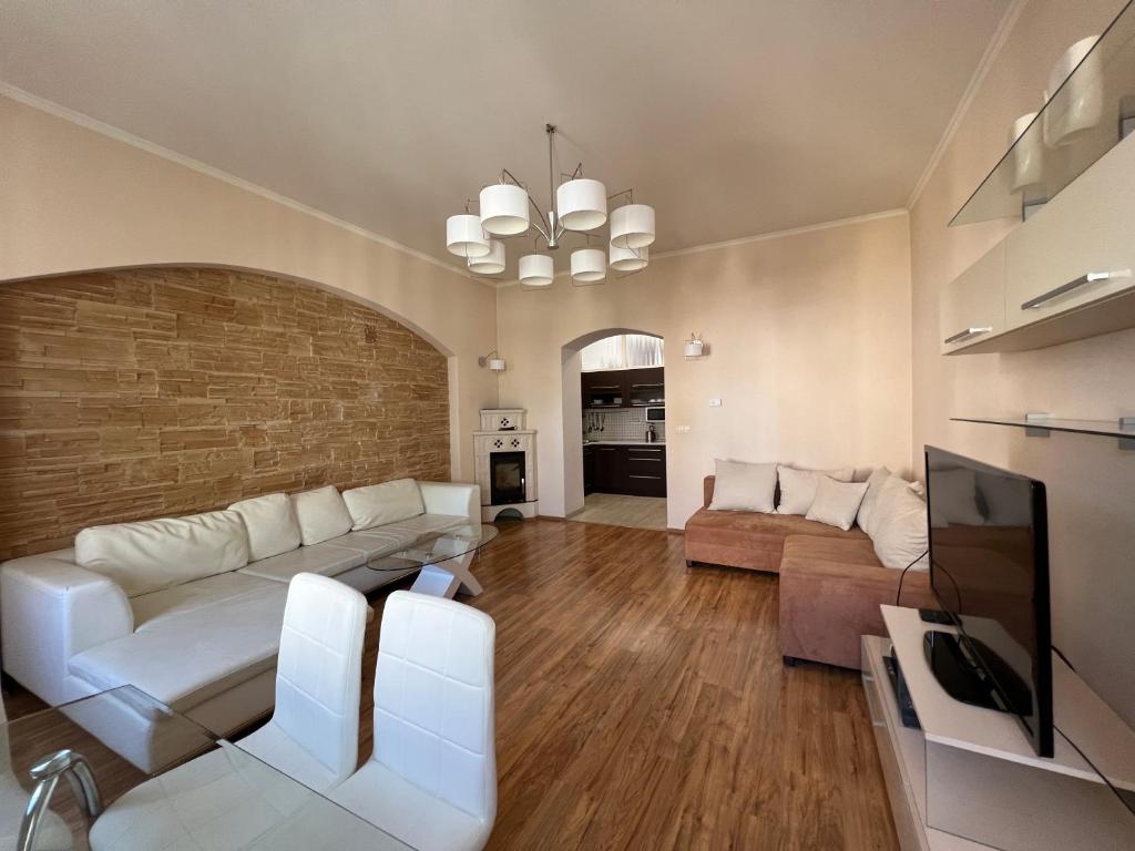 Il comprend un salon doté d'un mobilier blanc et d'un mur en briques. dans l'établissement Apartment DR. Becher LUX 60 M2, à Karlovy Vary