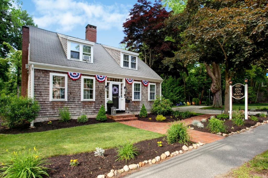 Uma casa com bandeiras americanas no jardim da frente. em Inn On Main em Yarmouth Port