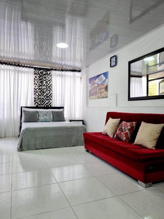 une chambre avec un lit et un canapé rouge dans l'établissement Apartaestudio ROMA 402 Edificio Europa Ibagué, à Ibagué