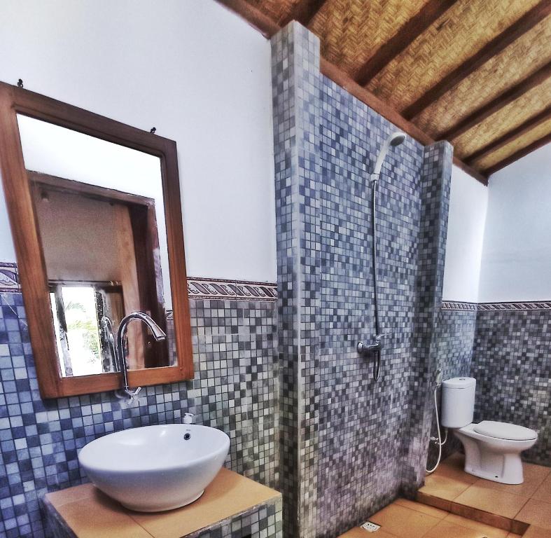 a bathroom with a sink and a shower with a mirror at Follow The Rabbit Bungalow in Gili Air