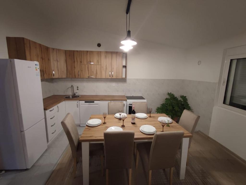 cocina con mesa de madera con sillas y nevera blanca en Guest House Tomba, en Bar