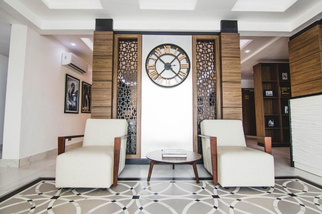 um lobby com duas cadeiras e um relógio na parede em BON Hotel Lekki Residence em Lagos