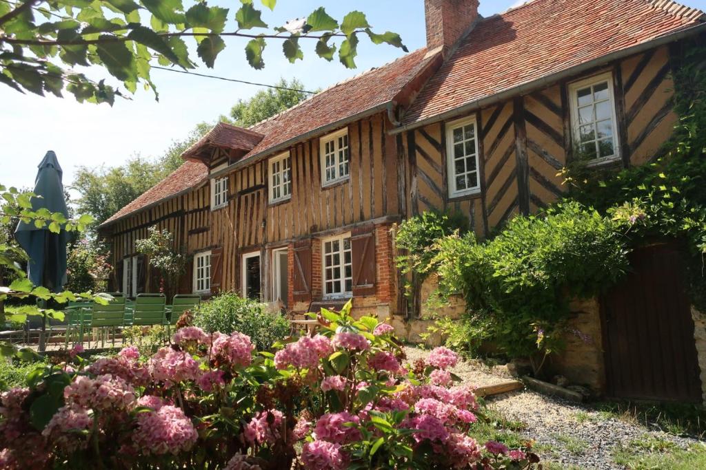 uma casa velha com flores em frente em Gite des Trévignes em Cambremer