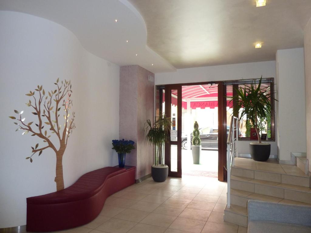 a lobby with a red couch and a tree on the wall at Alla Bianca Hotel in Marghera
