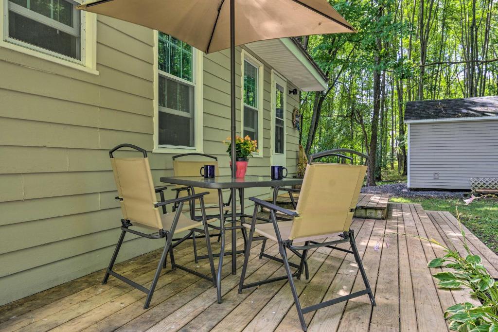 een tafel en stoelen op een terras met een paraplu bij Peaceful Finger Lakes Apartment with Patio! in Ovid