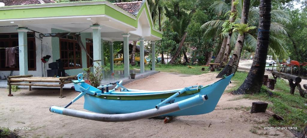 un bateau bleu garé devant un bâtiment dans l'établissement Homestay Buang Sari, à Gresik