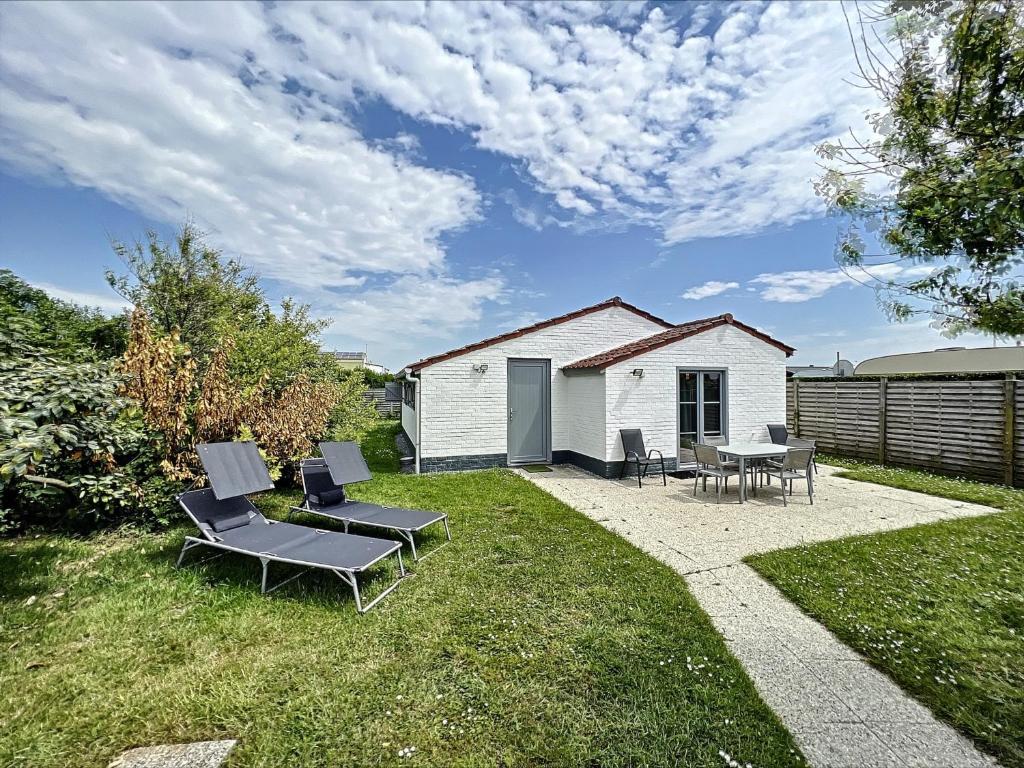 a patio with chairs and a table in a yard at Pur Sea vakantiehuis te Middelkerke / Westende in Middelkerke