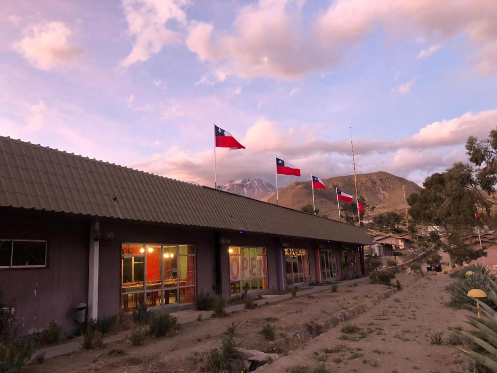 a building with three flags on top of it at Hotel Las Vicuñas in Putre