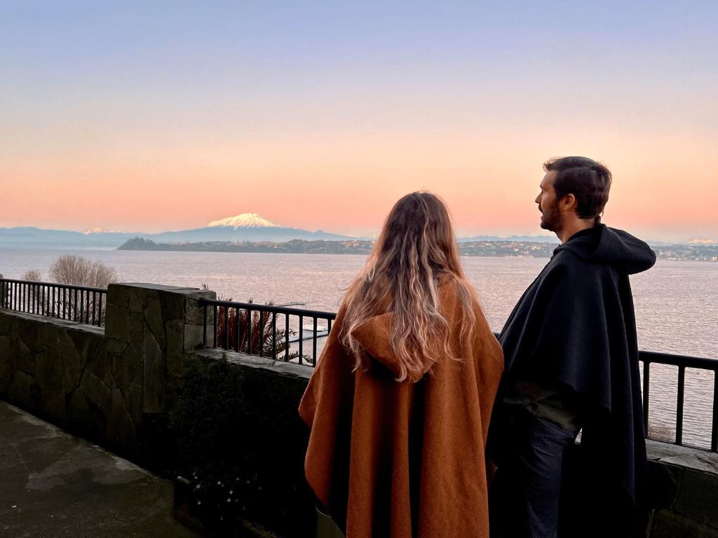 a man and a woman standing next to each other looking out over the water at Hotel Cabaña Del Lago Puerto Varas in Puerto Varas