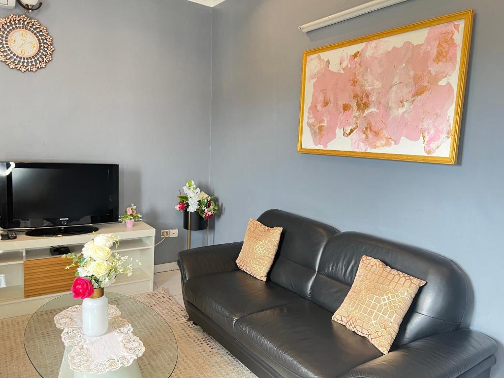 a living room with a black leather couch and a tv at Studio de haut standing, Bonamoussadi (Kotto) in Douala