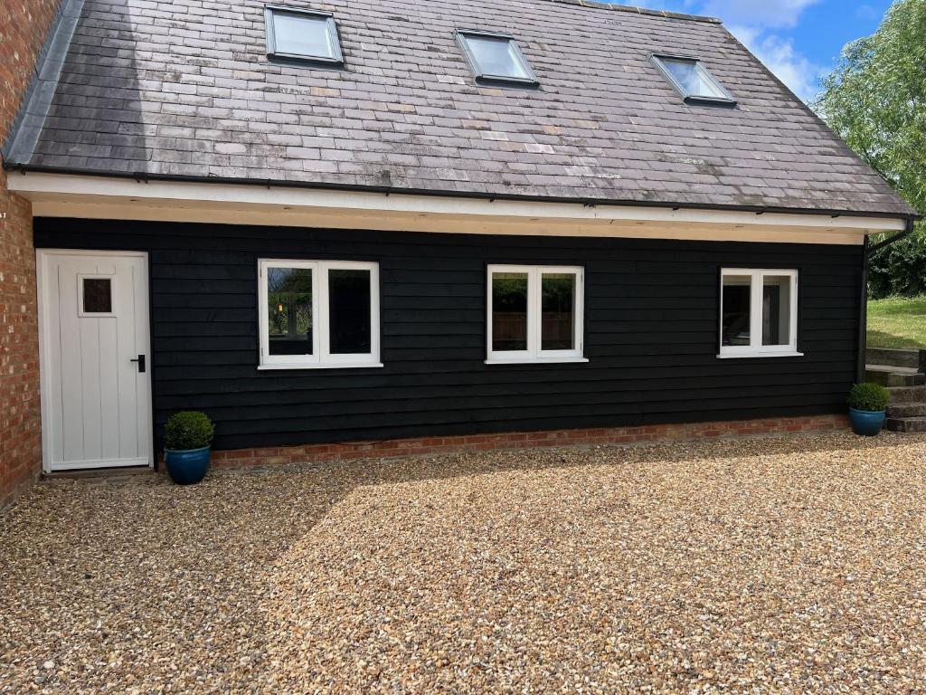 a black house with a white door and windows at A modern annex, in a tranquil countryside setting. in Aylesbury