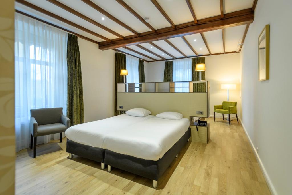 een hotelkamer met een bed en een stoel bij Parkhotel Valkenburg in Valkenburg