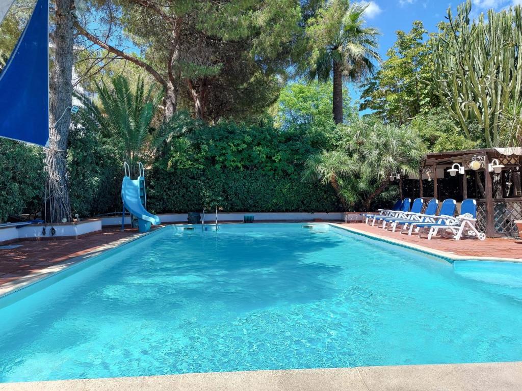 a swimming pool with a slide and chairs and trees at Oasis Green Villa in Palermo