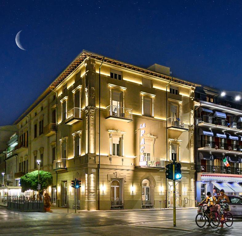 un bâtiment éclairé dans une rue de la ville la nuit dans l'établissement Hotel La Pace, à Viareggio
